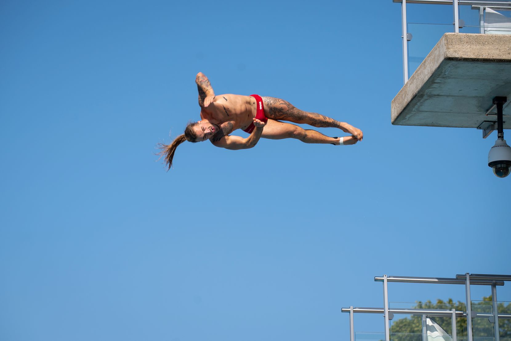 Ein Mann in Badehose springt von einem Sprungturm.